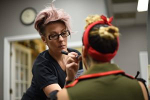 Closeup shot of pink haired woman applying makeup to another girl