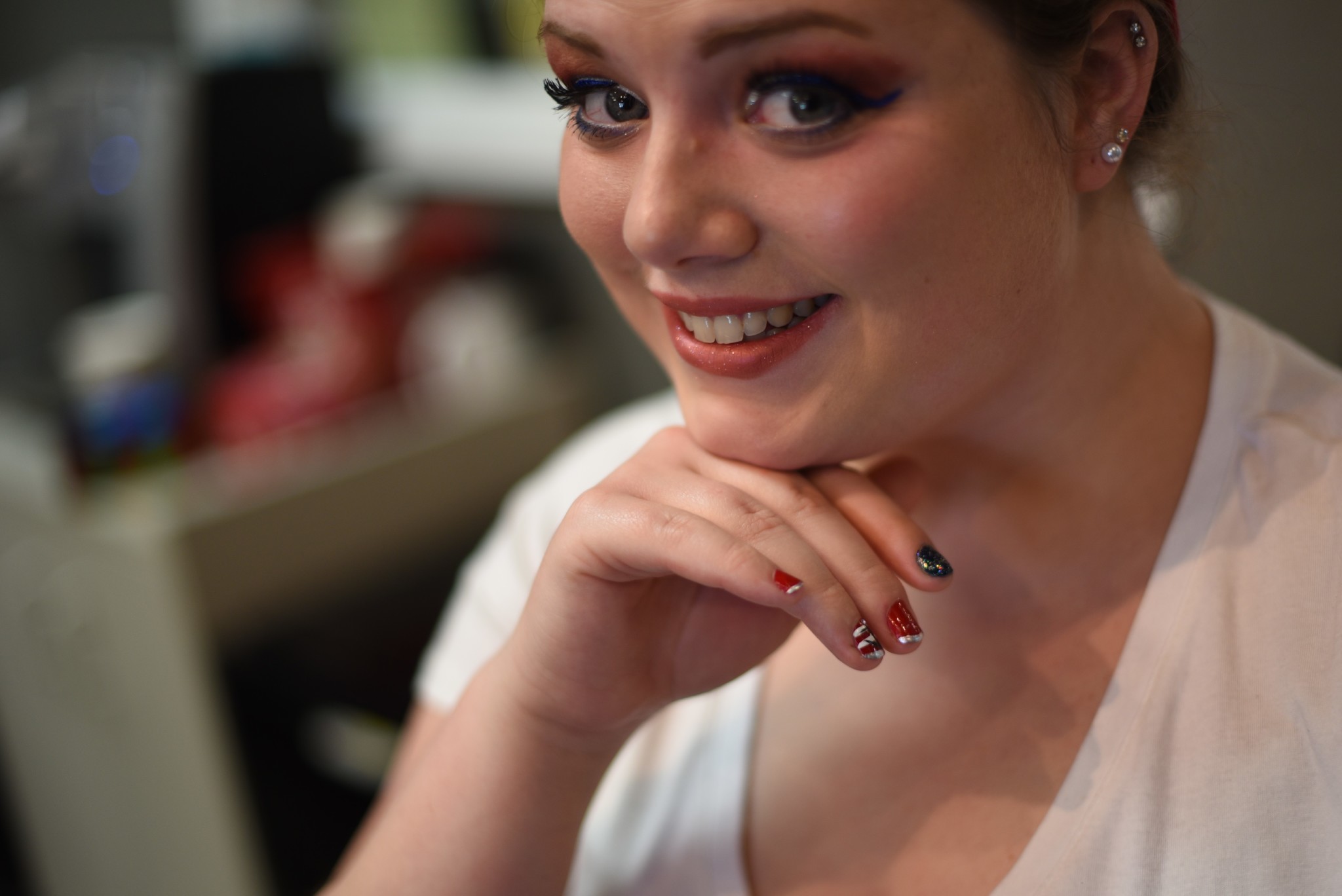 Woman smiling at the camera showing off her painted fingernails